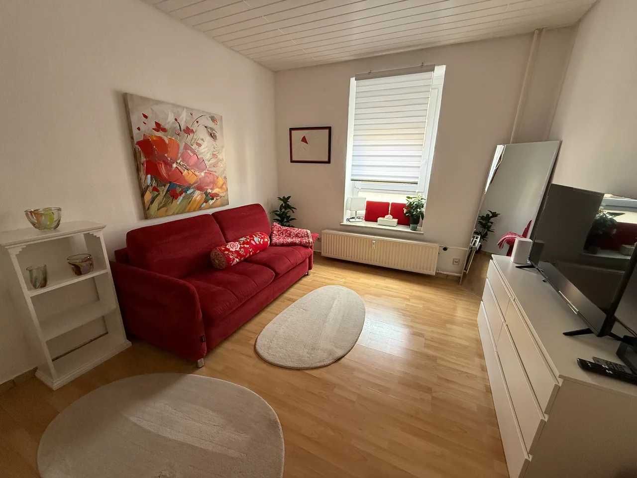 Wohnzimmer mit rotem Sofa in einer Bestandswohnung der Immobilien Werft in Kiel